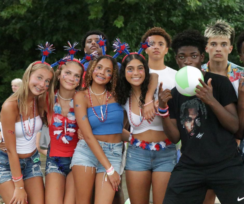 A group of teens in red, white, and blue smiling together