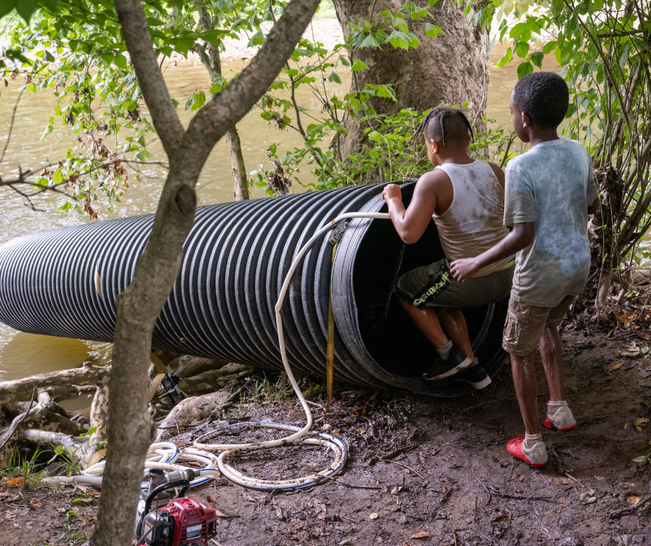 Two children gearing up to go down a tube slide into a river